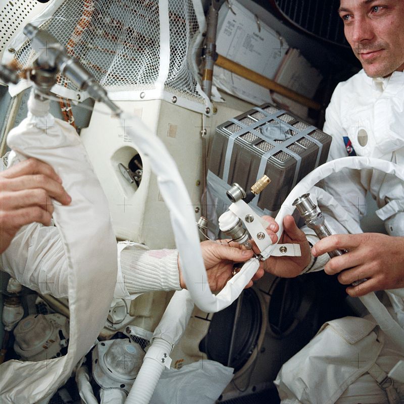 A tripulação da Apollo 13 com o sistema improvisado para circulação de ar, que foi chamado de "caixa de correios". (Fonte: NASA/Reprodução)