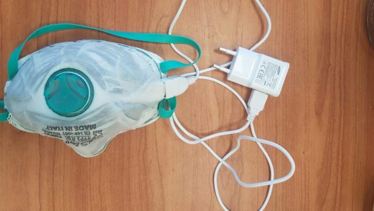 Máscara autolimpante tem porta USB na lateral para conectar o carregador à tomada.