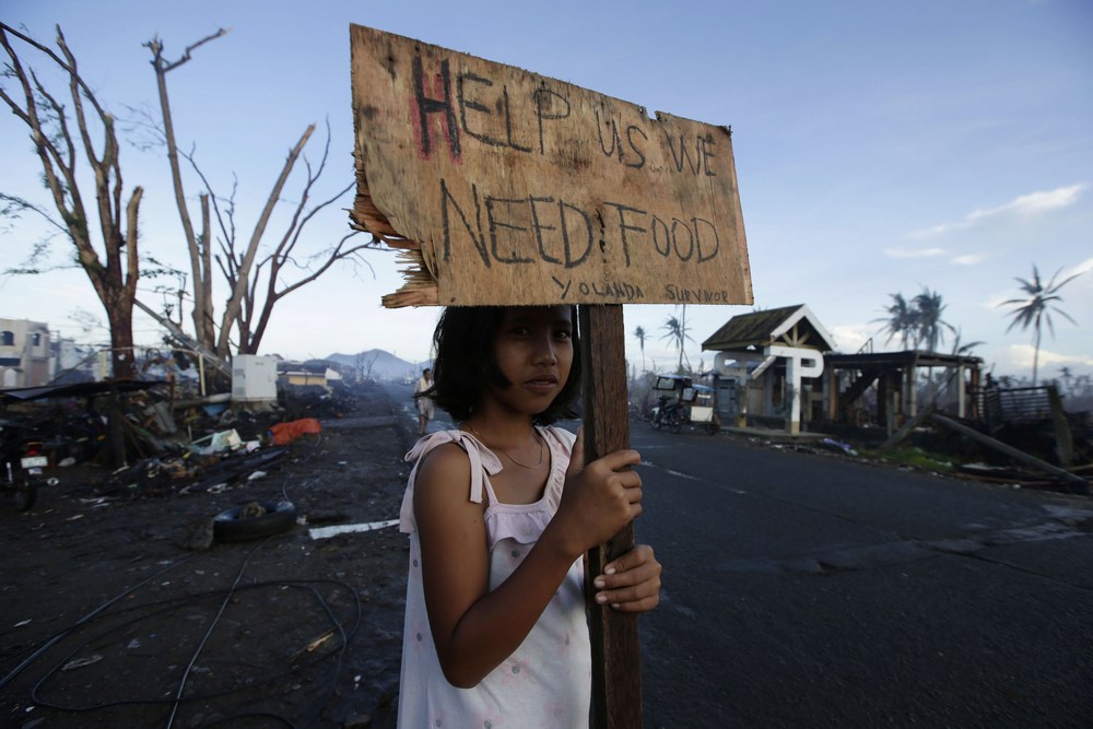 Uma sobrevivente pede ajuda à beira de uma rodovia no município de Palo, nas Filipinas, devastado pelo tufão Yolanda em 2013.