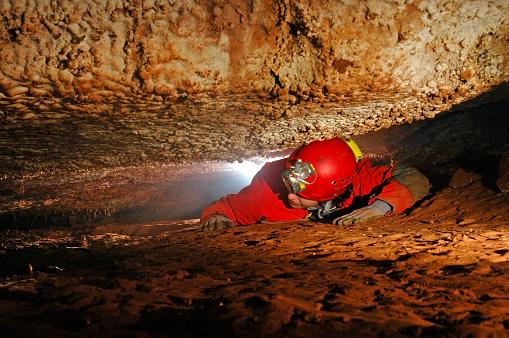 Um homem explora uma passagem estreita em uma caverna. (Fonte: Getty Images/Reprodução)